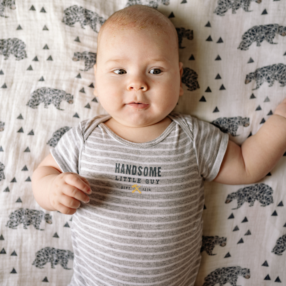 Baby wearing a 'Handsome Little Guy' onesie on a patterned blanket

