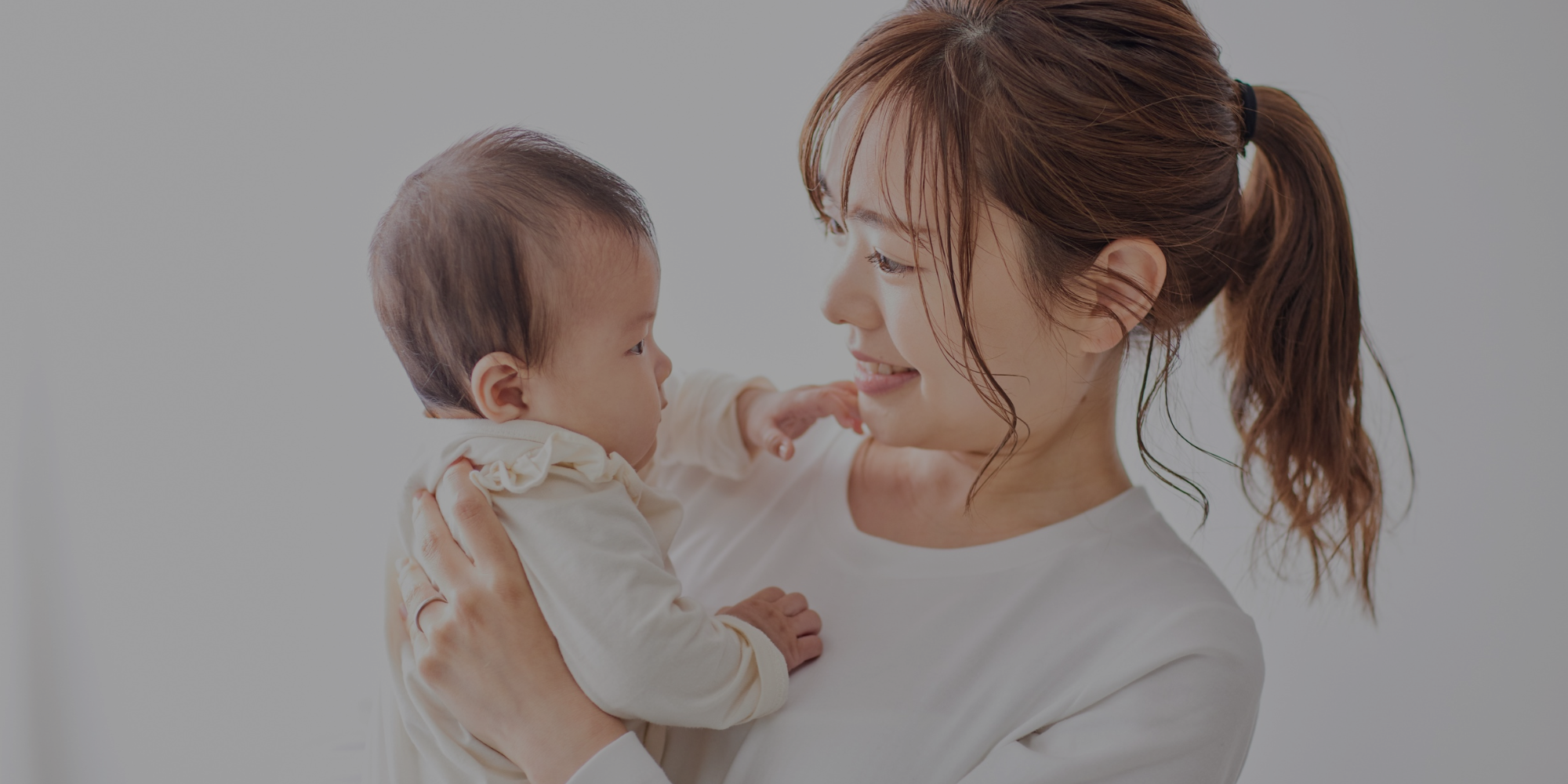 Woman holding a baby against a plain background

